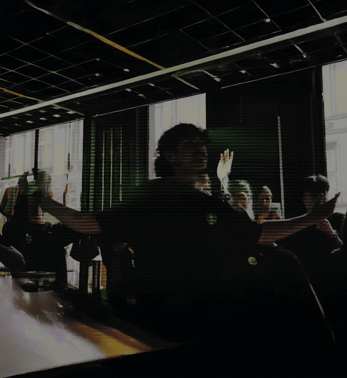 Cinematic shot of a man sitting with arms raised in a dimly lit studio during a creative campaign session.