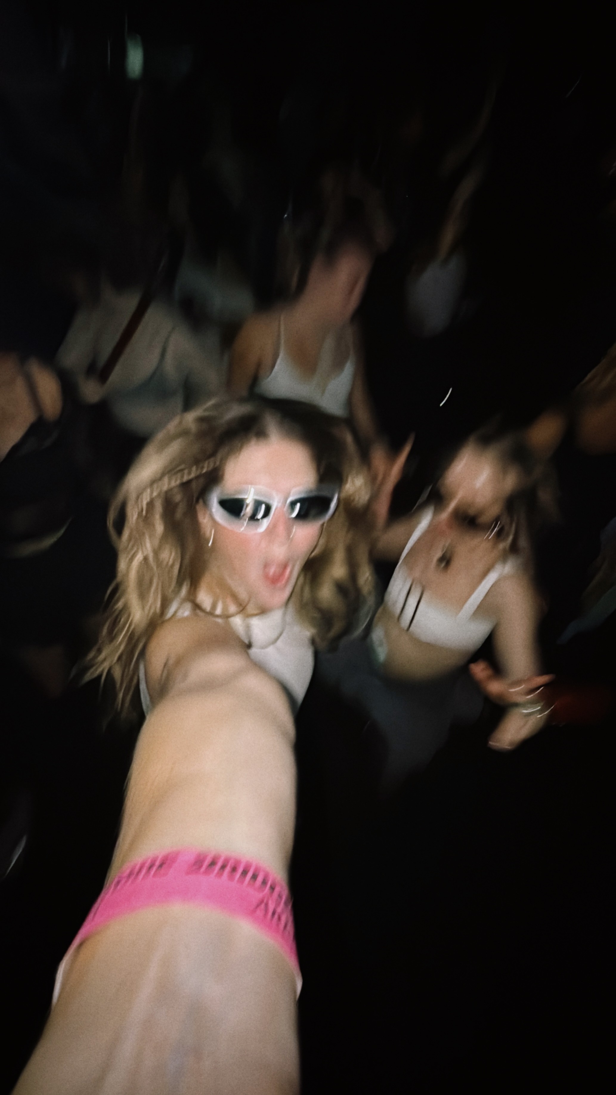 A blurry photo of three friends jumping up and down at a concert