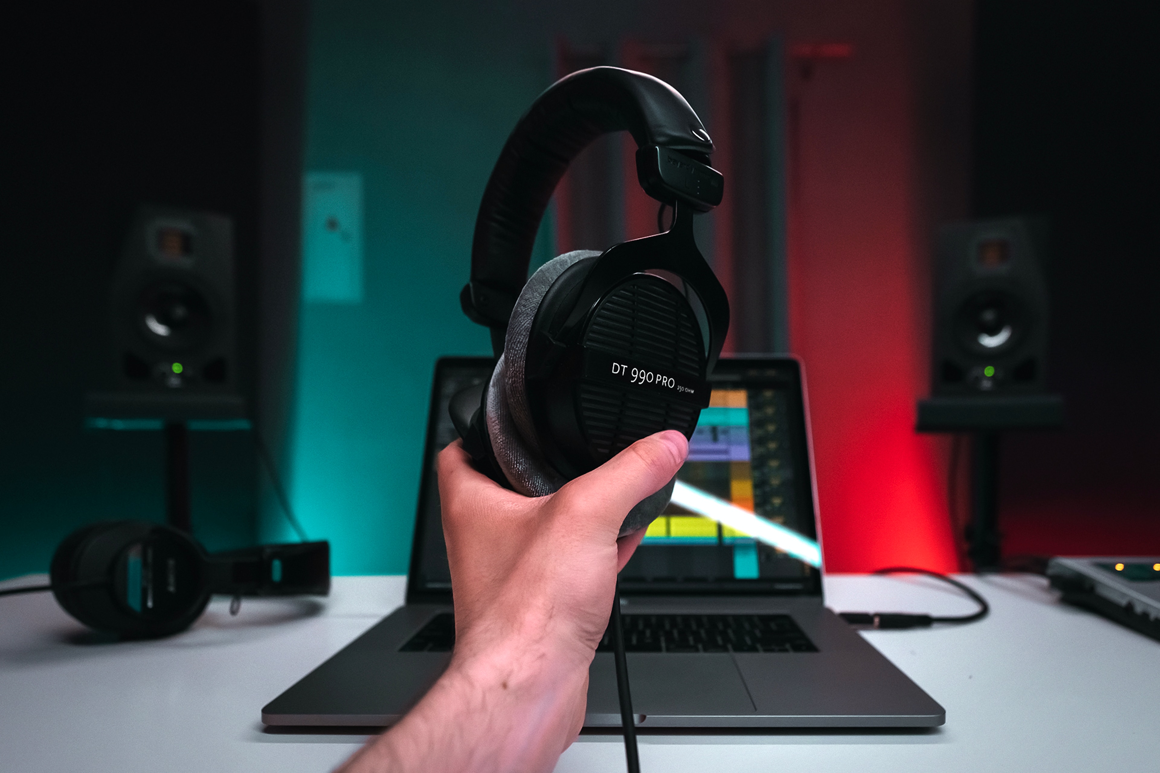 man holding headphones infront of his music editing laptop - how to write songs