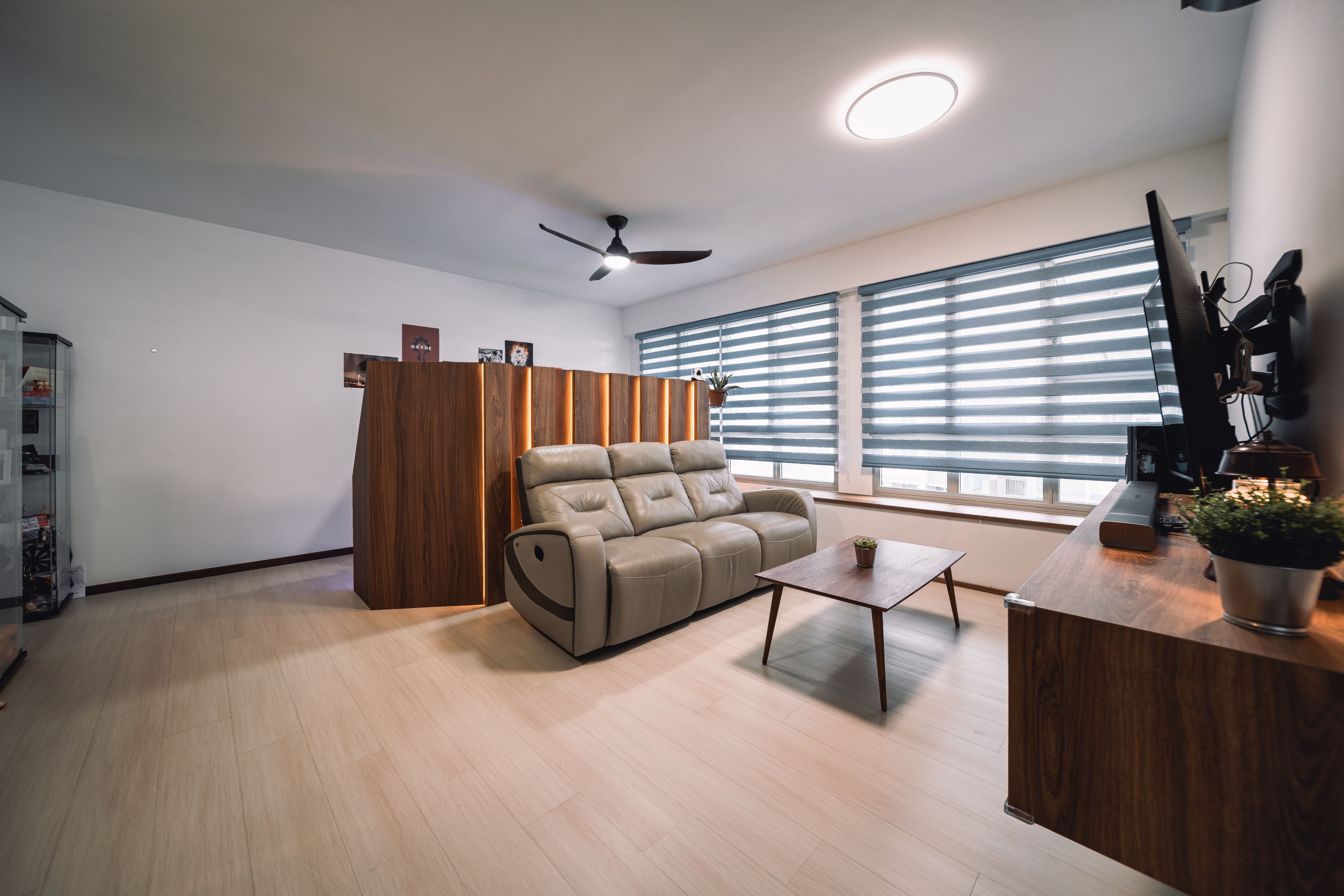 A cozy living space with recliner seating, warm wood paneling, and layered blinds for flexible daylight control.