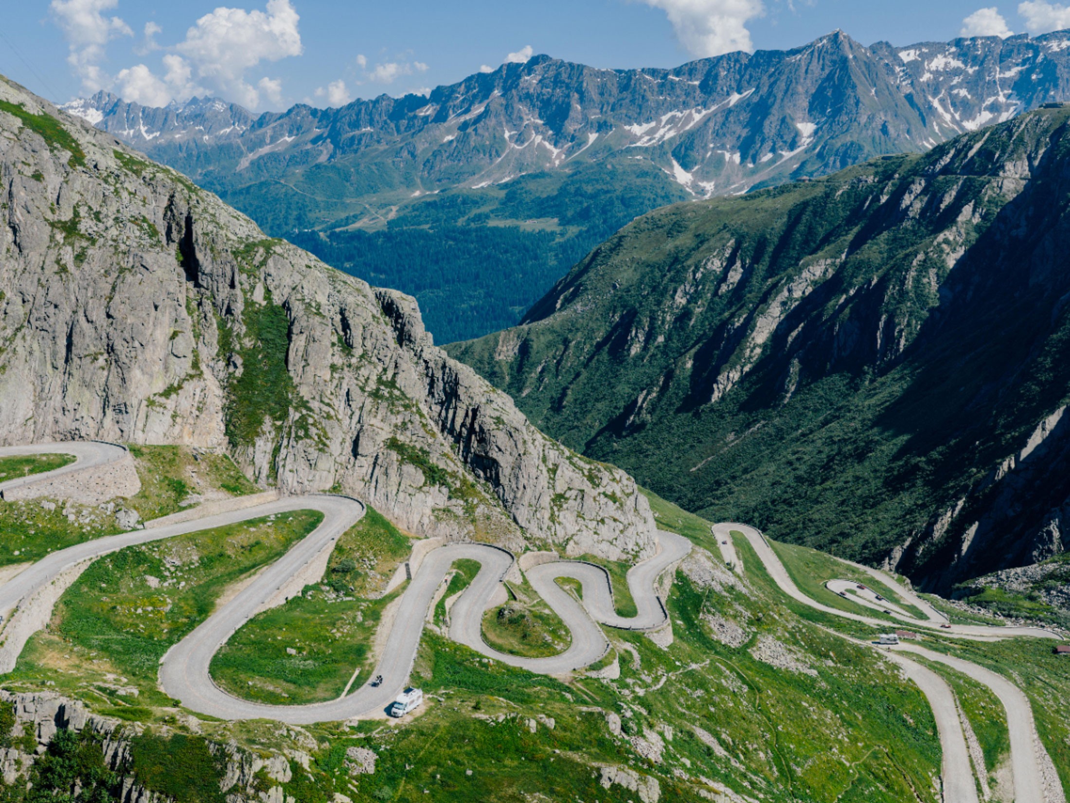 Two cyclists riding up a quiet mountain road in the Swiss Alps