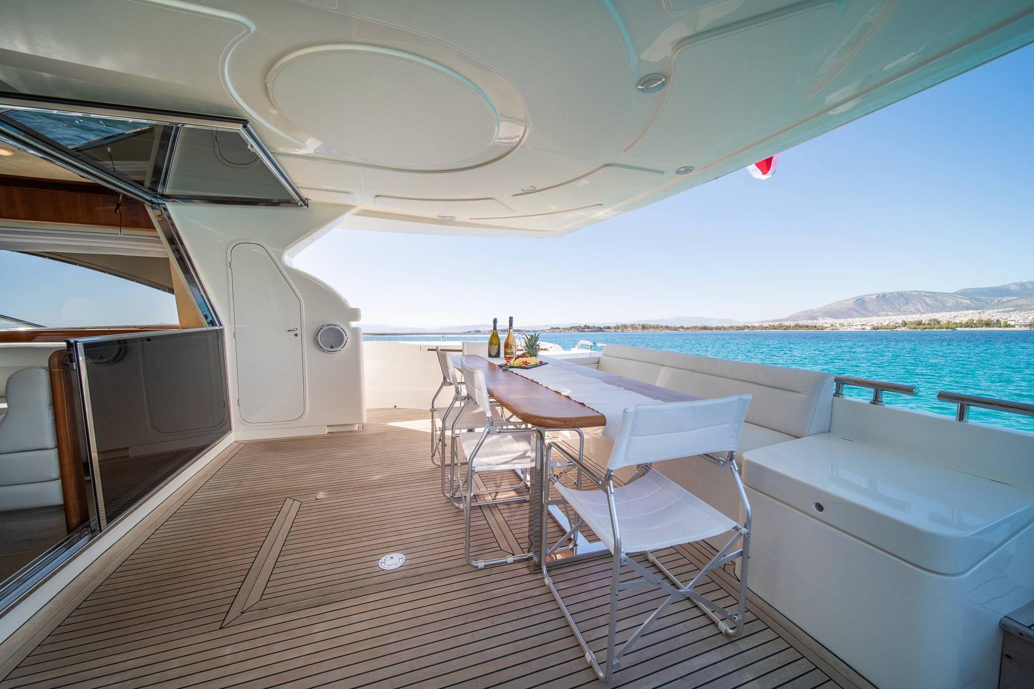 White Rock 36 speedboat with captain at helm cruising calm blue waters near Paros coastline with hills in background.