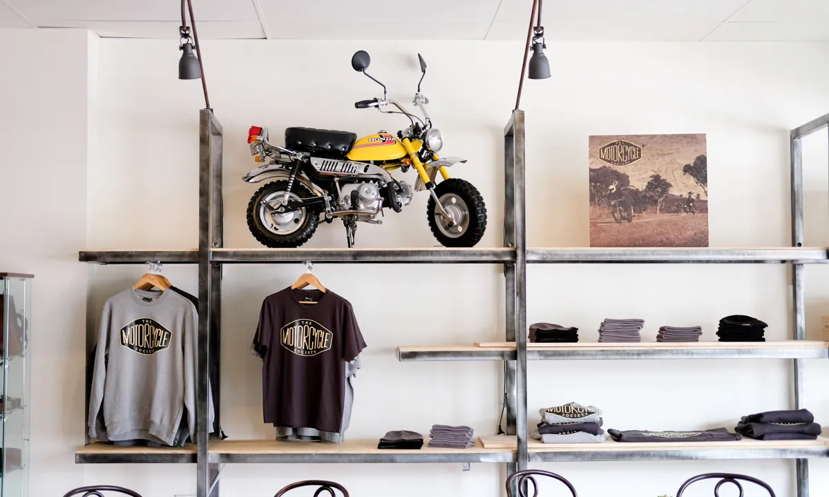 Inside of the motorcycle society shop, tshirts and motorcycle hanging from shelves