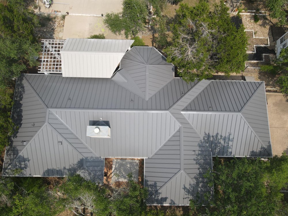 Large hip and valley roof with charcoal-colored standing seam panels, offering a sleek and durable design.