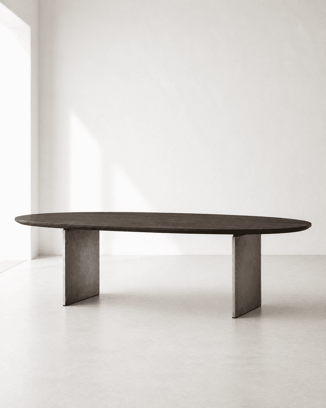 Elliptical dark-oak dining table with exactly two metal fin supports in a white gallery
