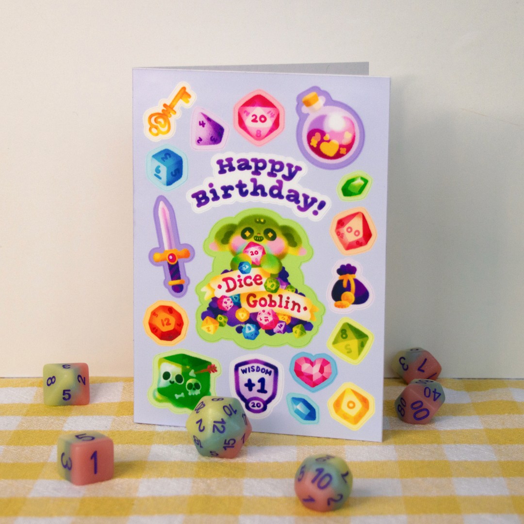 A light purple birthday card that is also a sticker sheet. In the centre is a goblin holding several tabletop gaming dice, with the words "Dice Goblin". Other small stickers on the card include other Dungeons and Dragons references, such as a gelatinous cube, a potion, and a sword.