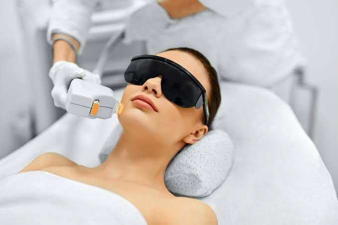 A woman laying in bed with a thermometer in her mouth
