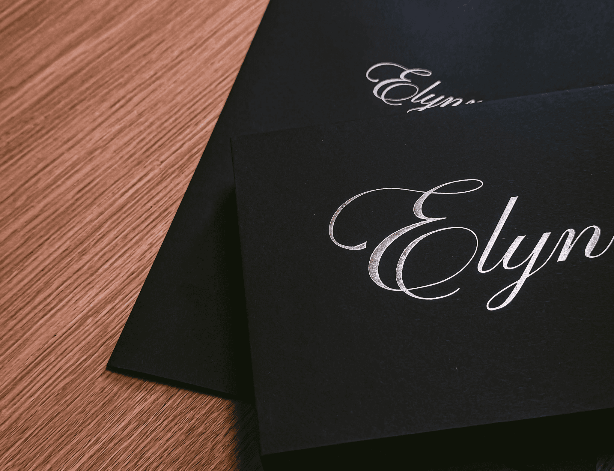 Packaging et papeterie de luxe de la marque Elynn avec logo argenté sur fond noir.