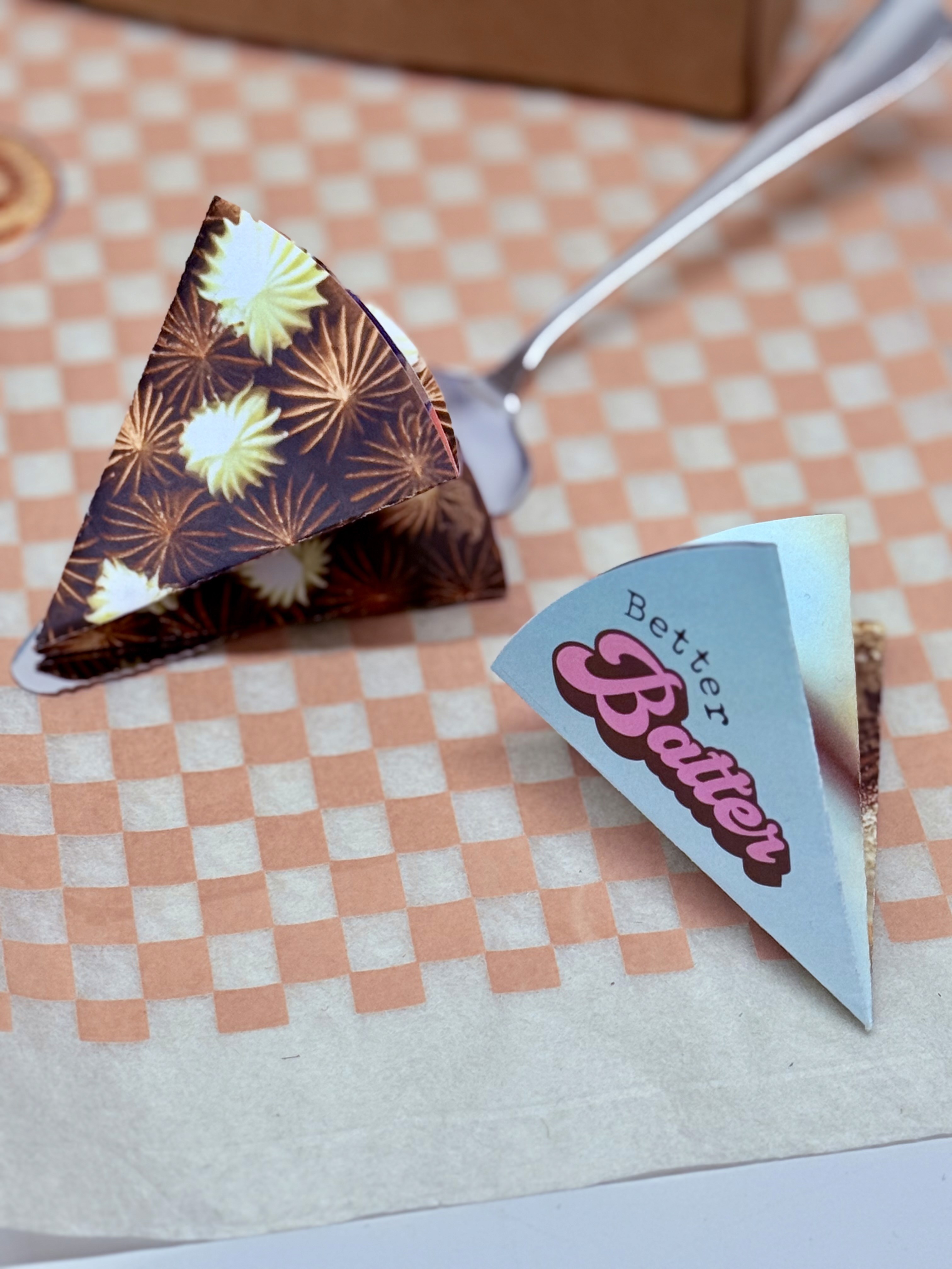 Stylish high-top sneakers featuring a combination of brown, cream, and navy blue leather details, worn with dark rolled-up jeans on a rustic wooden floor.