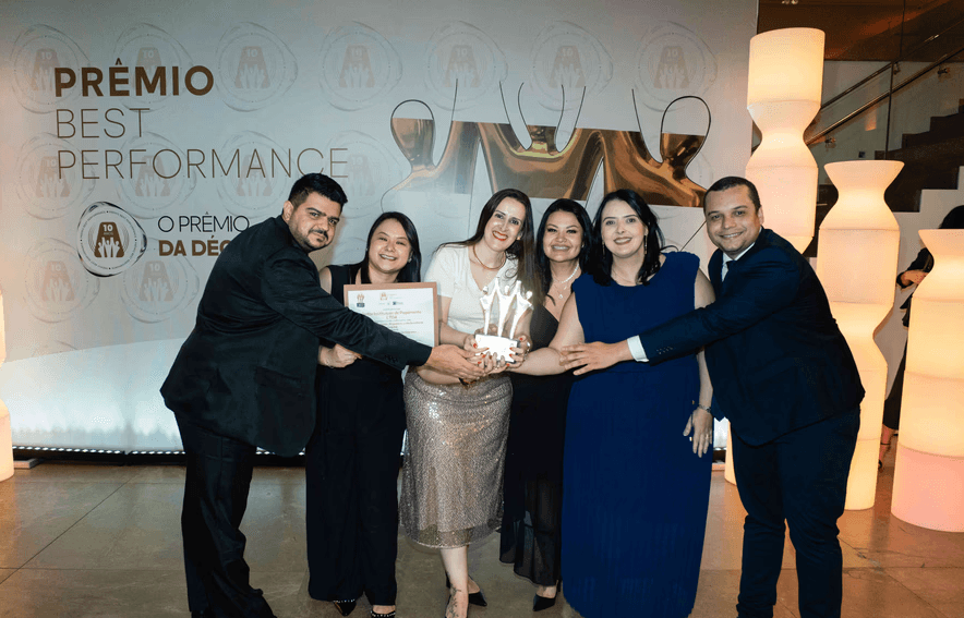 Executivos da Jeitto posando com troféu ouro e certificado no palco do Prêmio Best Performance 2025