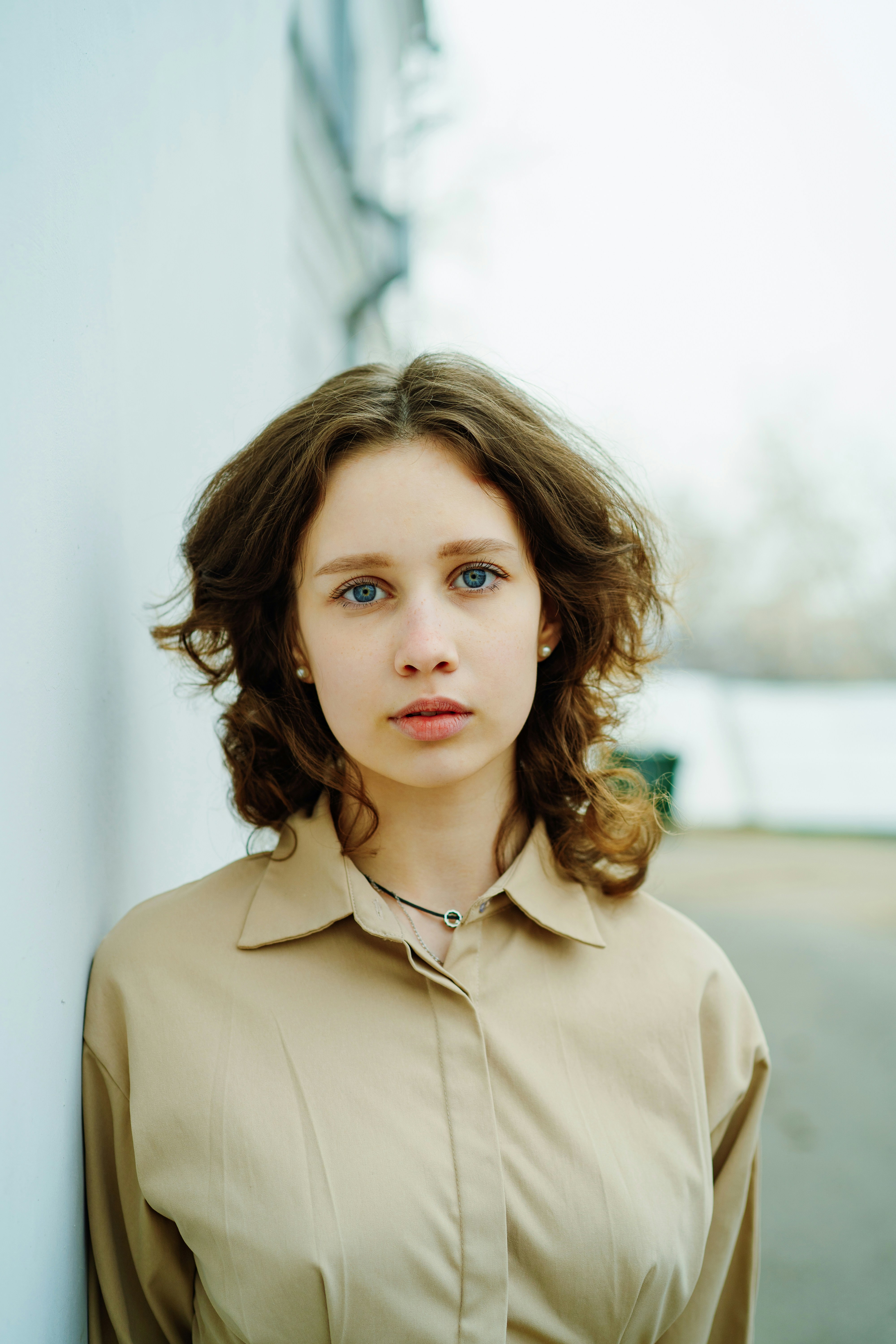 a woman standing next to a white wall