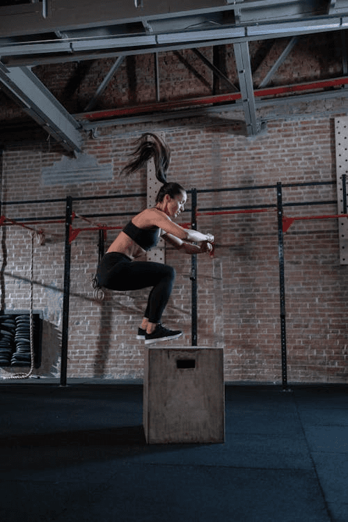 Woman performing a box jump as part of a HIIT exercise routine.