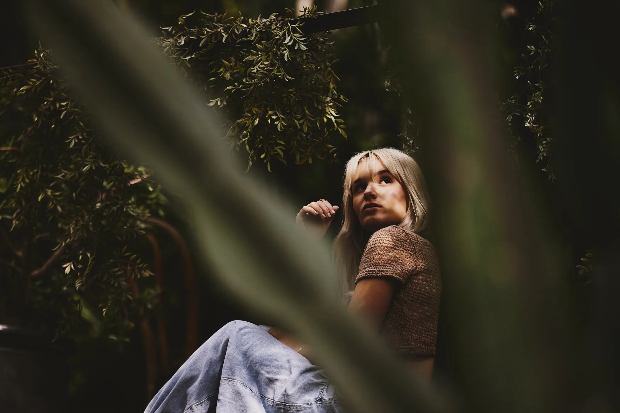 blonde woman glancing up through foliage — portrait photography by Tom Kubik
