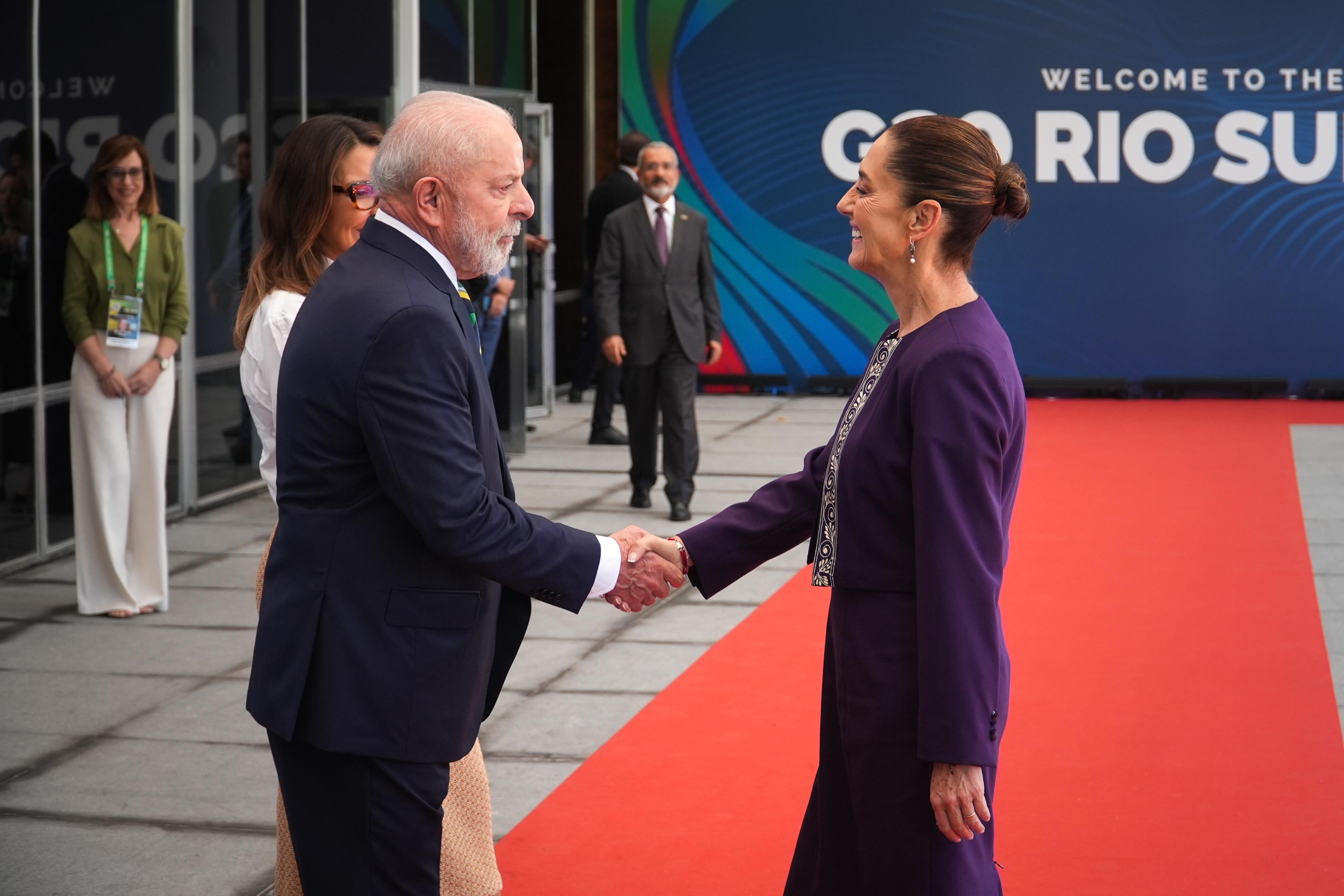 Mexican President Claudia Sheinbaum greets Brazilian President Luiz Inácio Lula da Silva with a handshake on a red carpet at the G20 Summit.