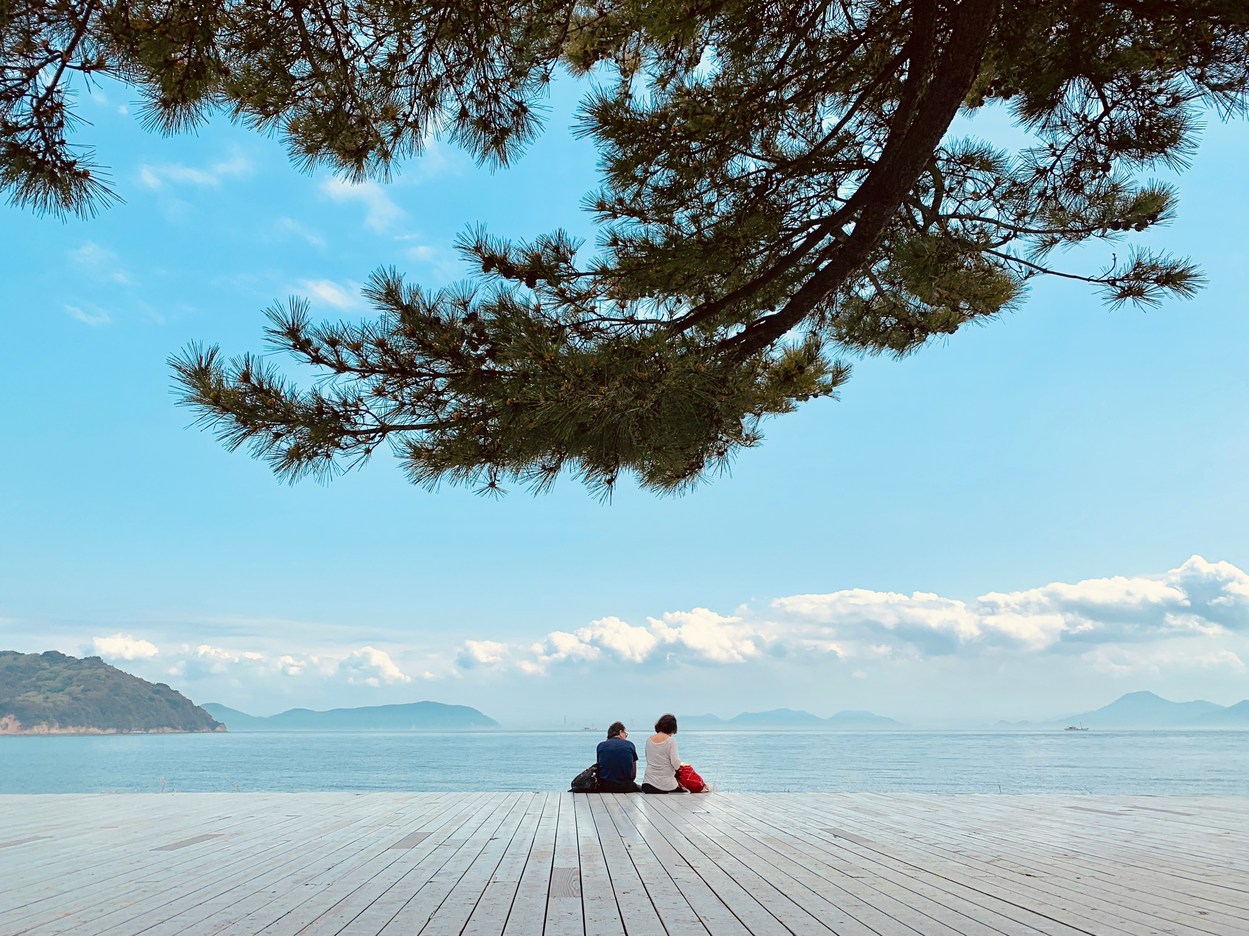 person sitting on white snow covered ground near body of water during daytime