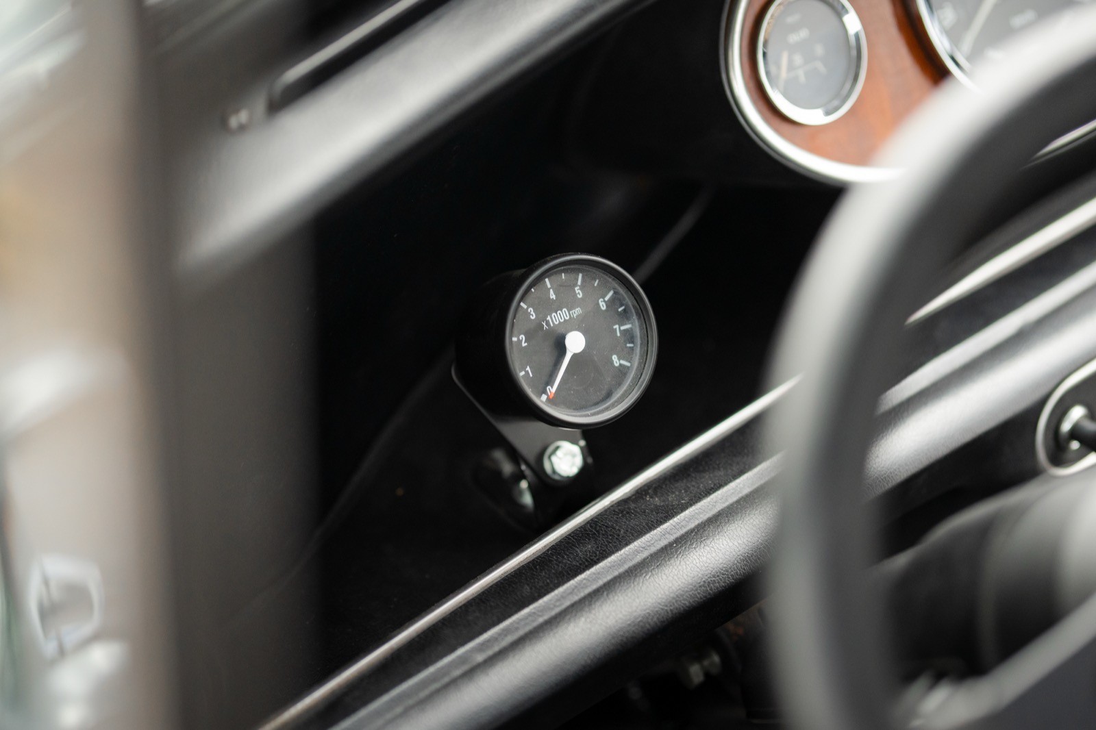Close-up of a car dashboard, featuring gauges and controls in a black interior setting.