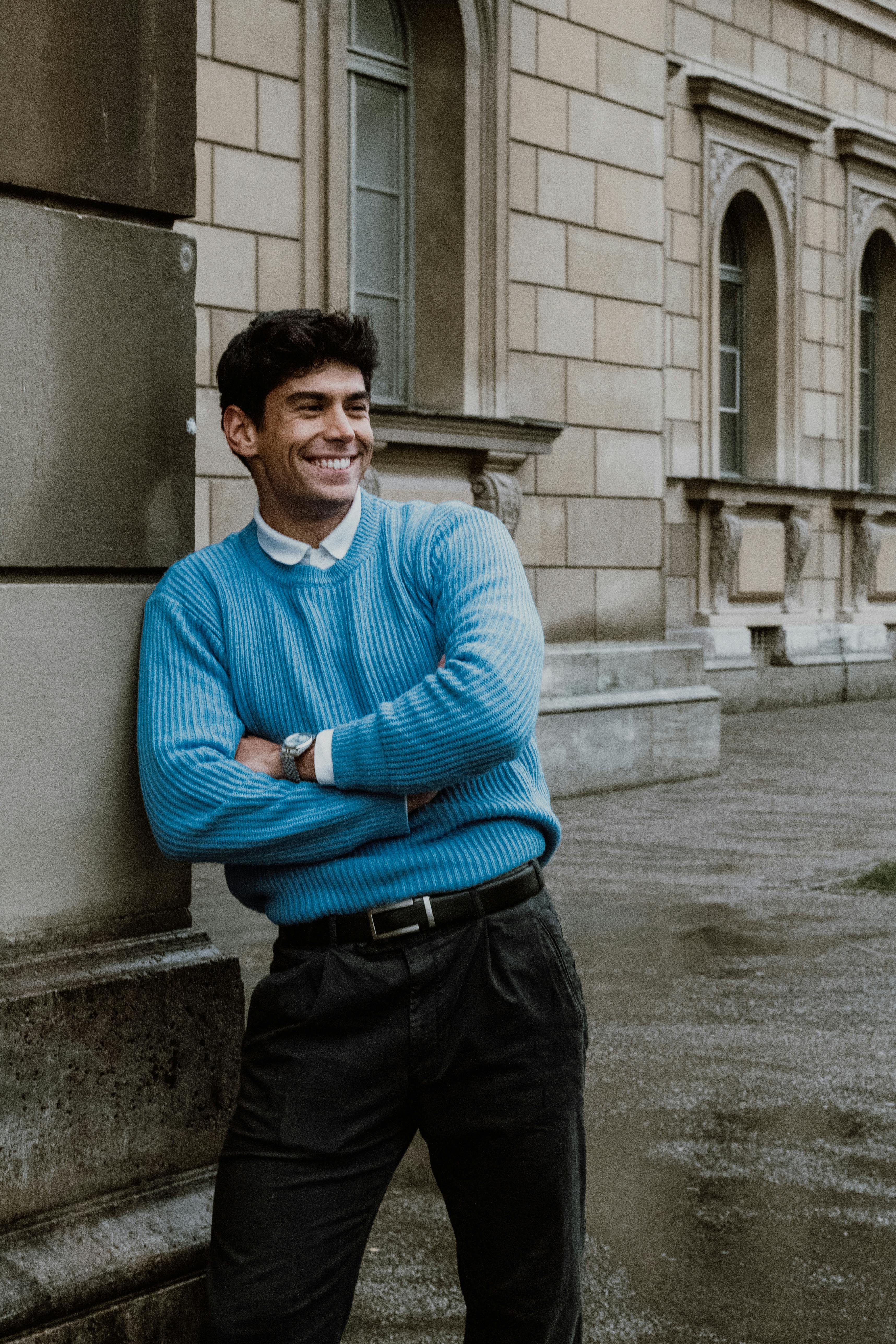 man wearing black crew-neck shirt and black cap in front of glass wall