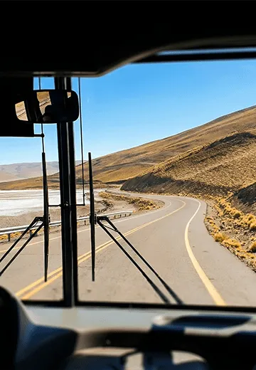 Vista da estrada sinuosa em região montanhosa observada do interior do ônibus durante o trajeto do roteiro