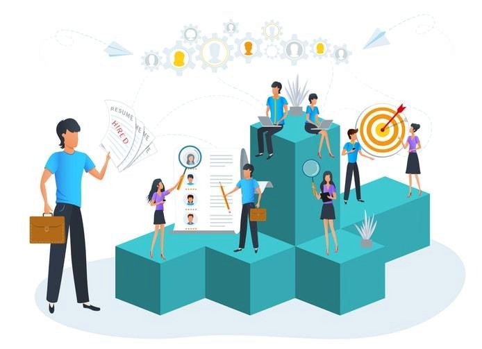 A diverse group of professionals, including men and women of various ethnicities, is engaged in a lively discussion around a conference table, reflecting a collaborative company culture. They appear to be sharing insights about job responsibilities and the hiring process, indicating a focus on professional development and team dynamics.