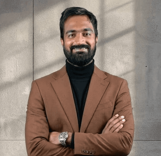 Portrait of Ashutosh Singh, Co-founder & CEO, wearing a black t-shirt with 'Follow the Leader' text, smiling against a light purple gradient background.