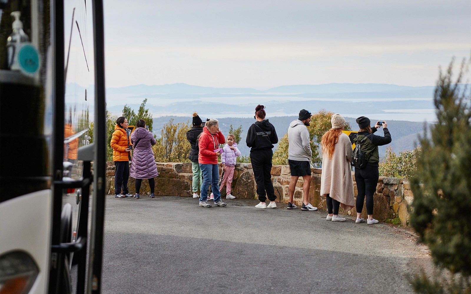 Tour group enjoying scenic view from Mt Wellington lookout.