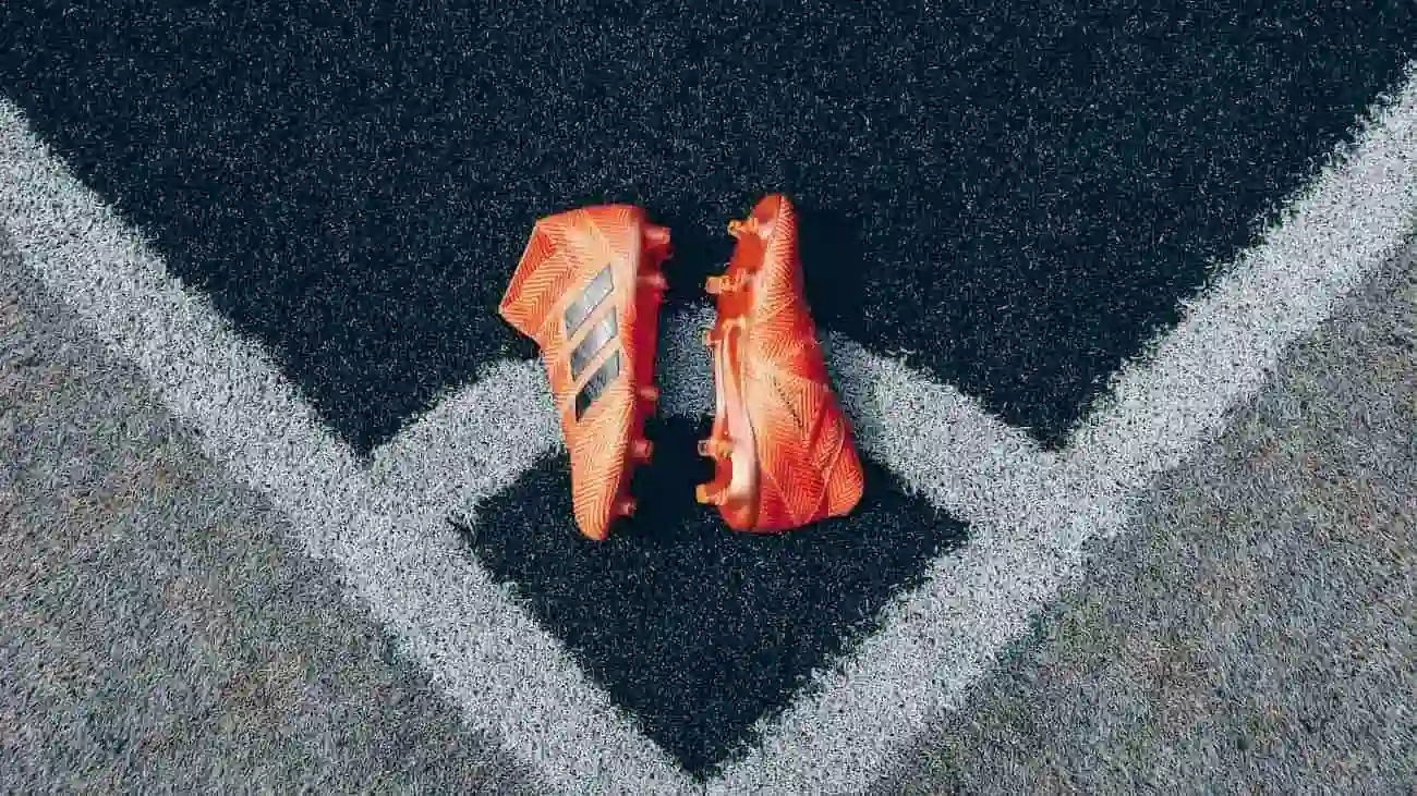 Football boots placed on a pitch line symbolise the preparation for a football match, with the focus on using the CoachingArea platform to organise friendly matches and tournaments.