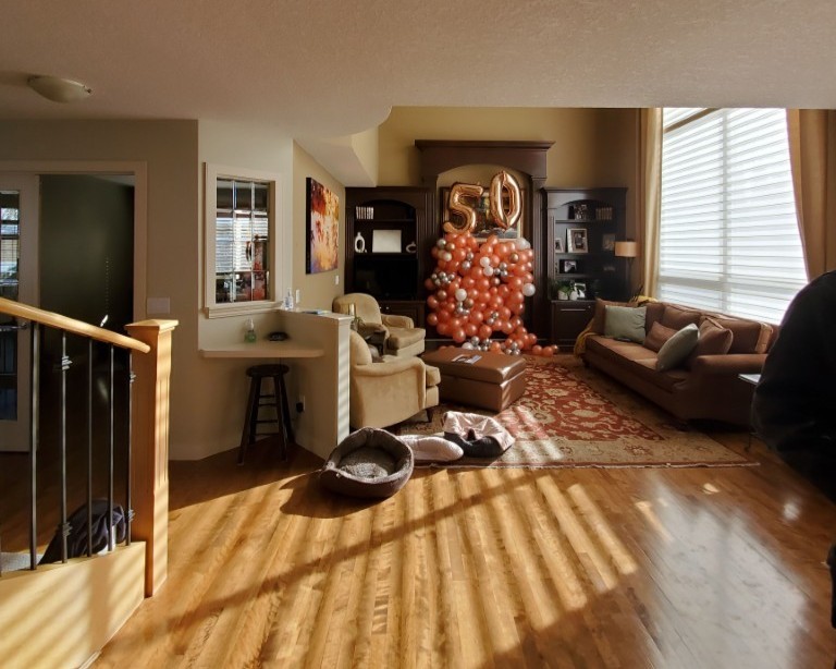 A living room filled with 50 birthday decor. The living room has maple flooring, and some oler built in entertainment units. It feels dated and not quite put together.