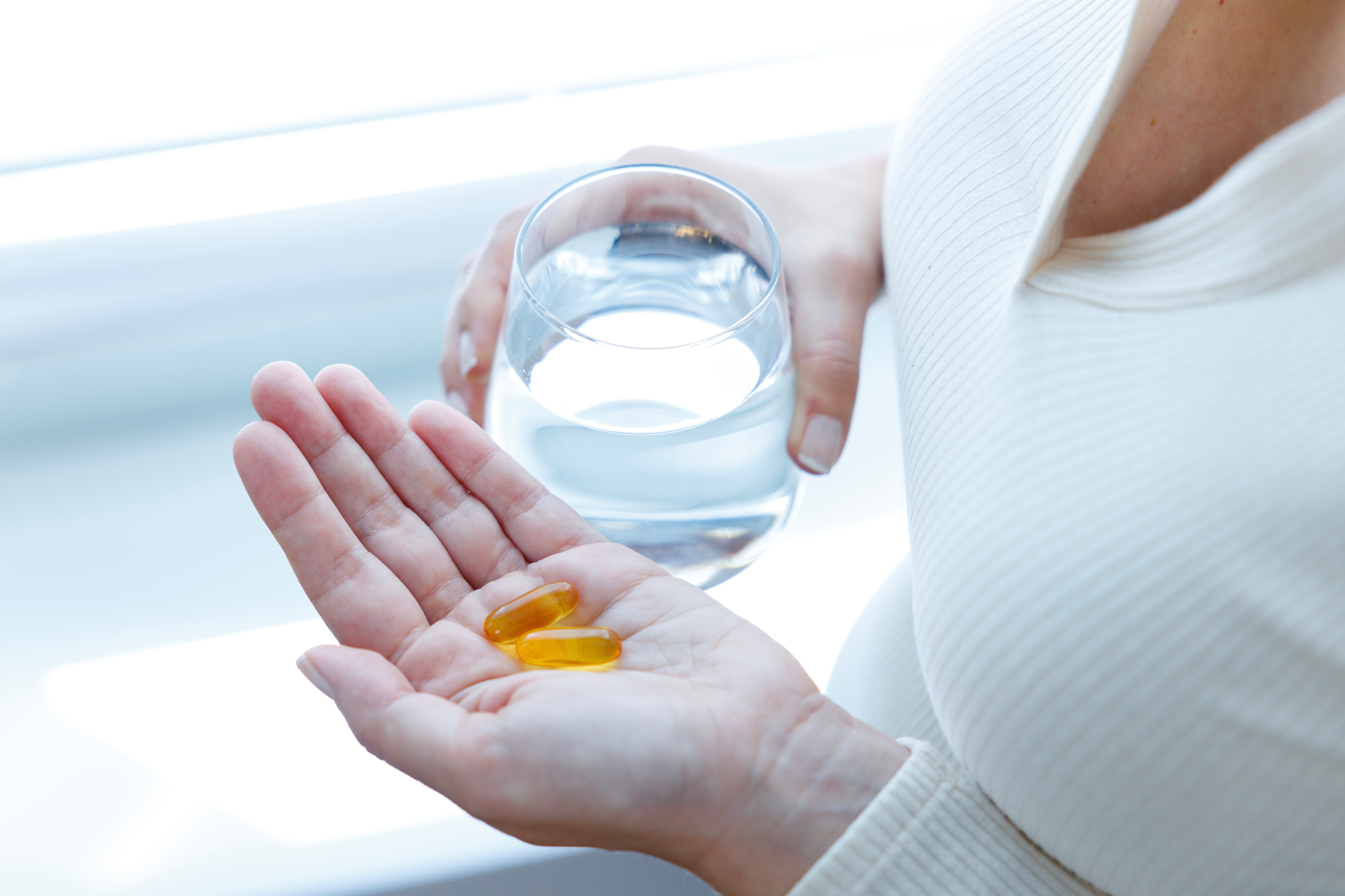 Woman holding capsules with a glass of water
