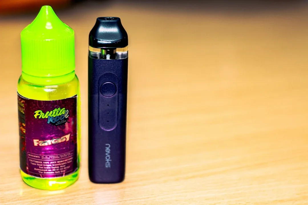 an electronic device next to a bottle on a table