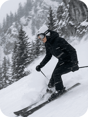 Woman skiing downhill, alpine winter landscape with snow-covered trees