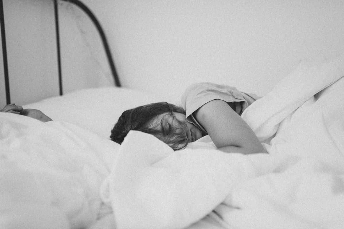 Femme dormant paisiblement dans un lit blanc