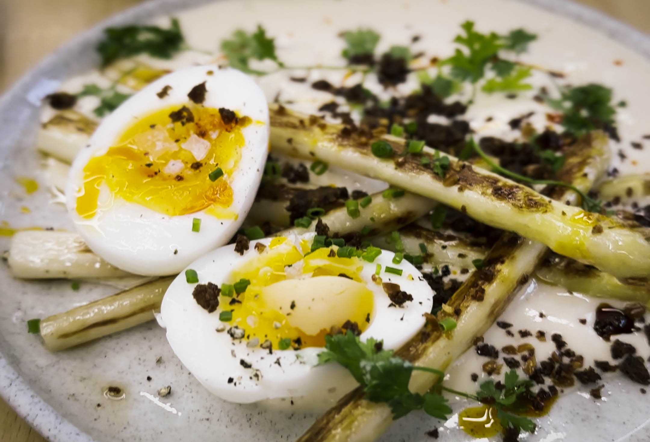 soft eggs served with charred veggies on a white plate