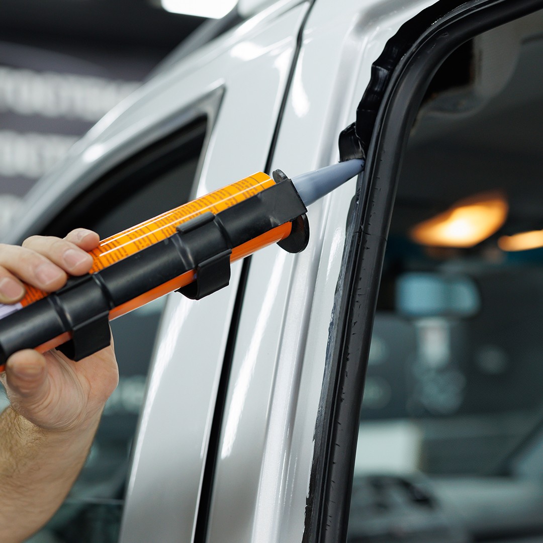 Techniker trägt Dichtmittel bei Autoglas-Reparatur auf – schnelle Hilfe bei Glasschäden KulXpert Bonn Rhein-Sieg