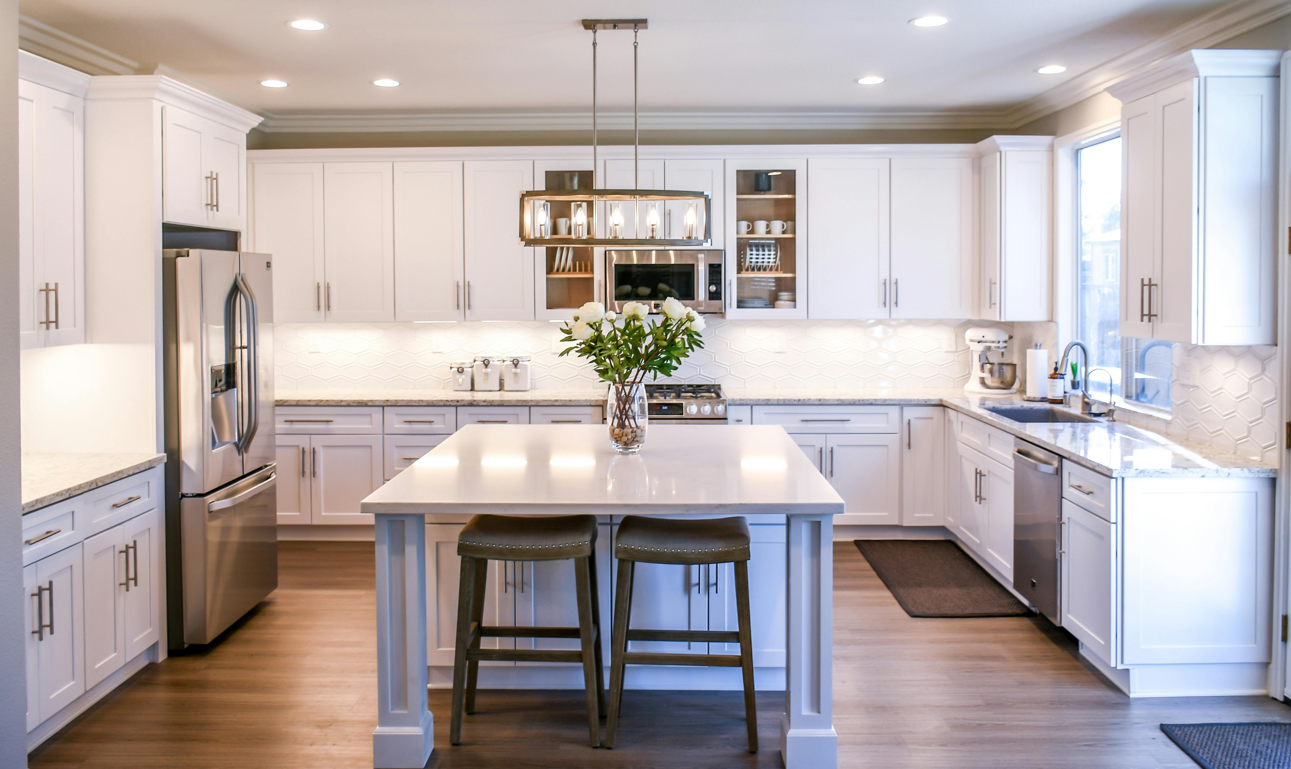 Spacious, luxurious living room with high ceilings, an elegant beige sectional sofa, warm ambient lighting, classical artwork, and rustic architectural elements, featuring an open layout with a view of a mezzanine level.