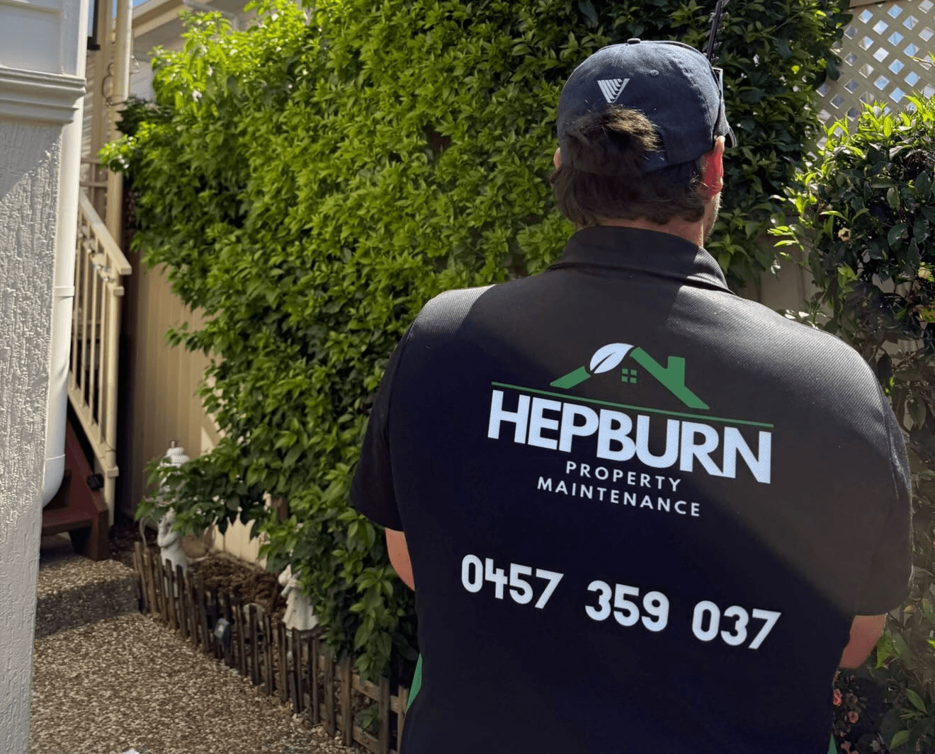 Hepburn Property Maintenance team member assessing overgrown hedge at residential property Gold Coast