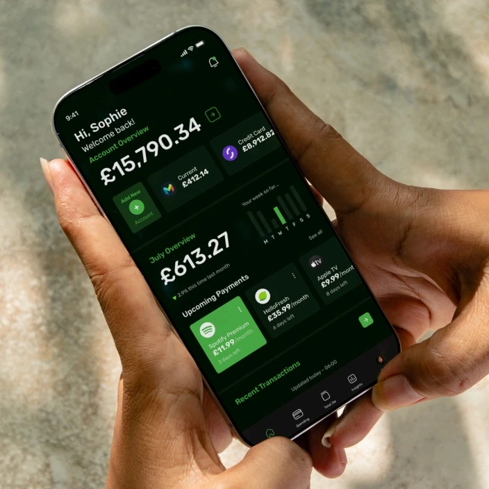 Hand holding iPhone displaying Pickle money management app with dark mode interface showing total balance and upcoming payments
