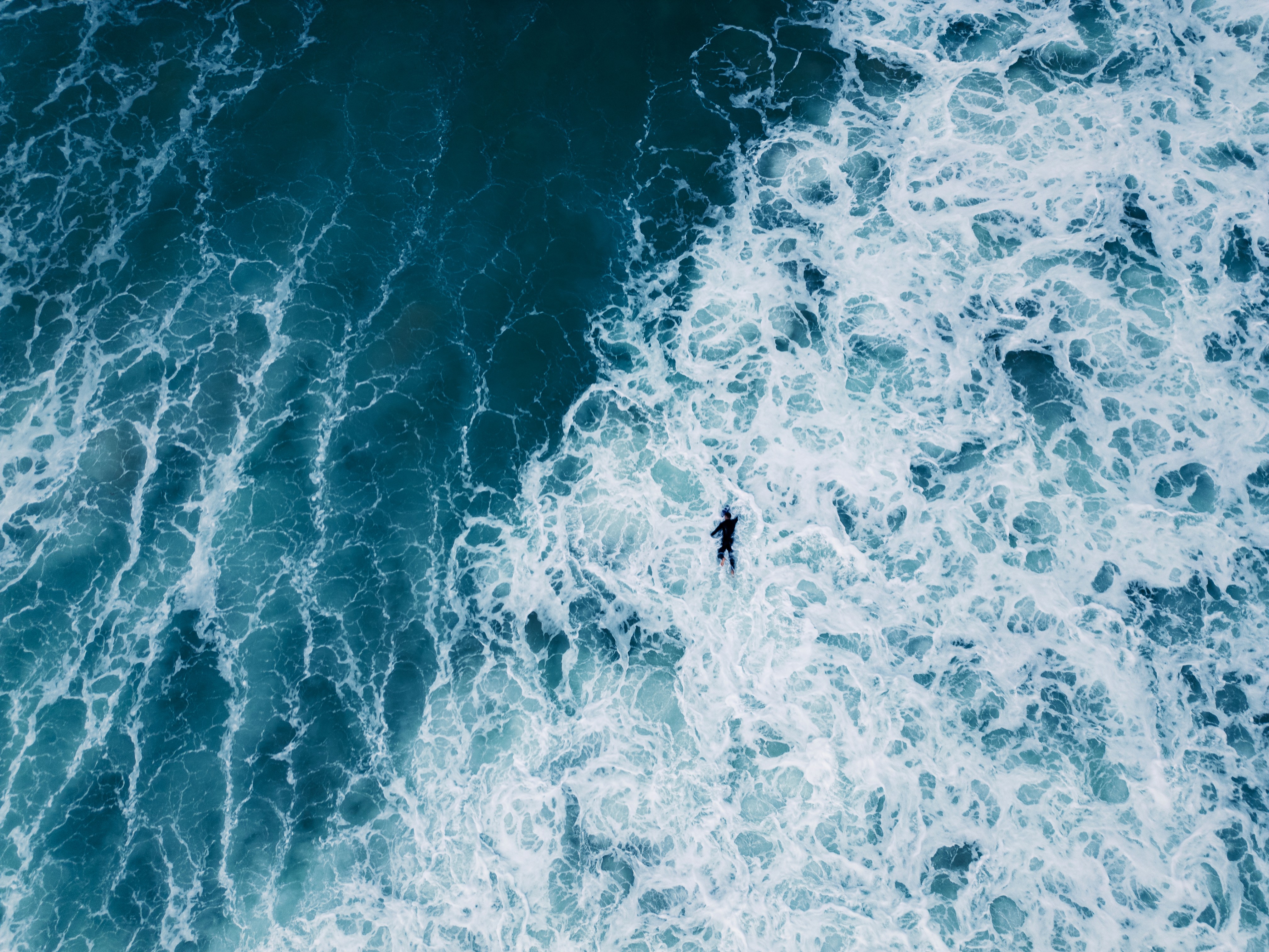 Drone photo looking down at a surfer in waves.
