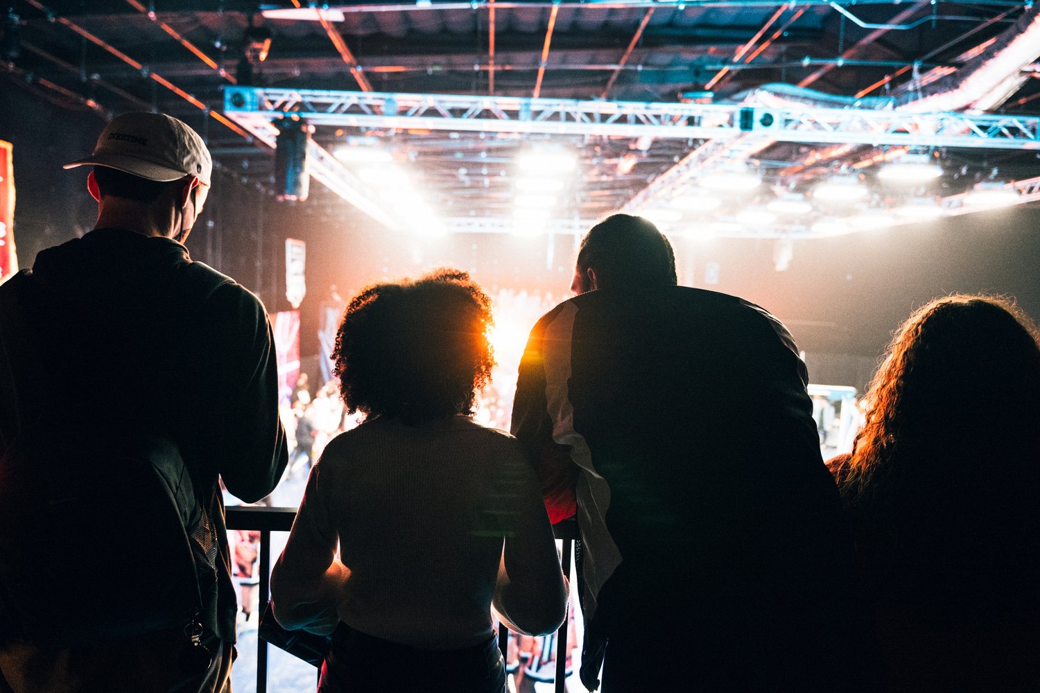 Close-up portrait of a person wearing a gray insulated hooded jacket with the hood up, showing their face framed by the hood against a light background.