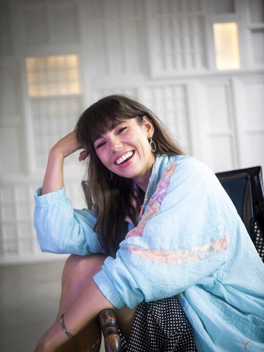 A person in a blue outfit smiling and leaning down.