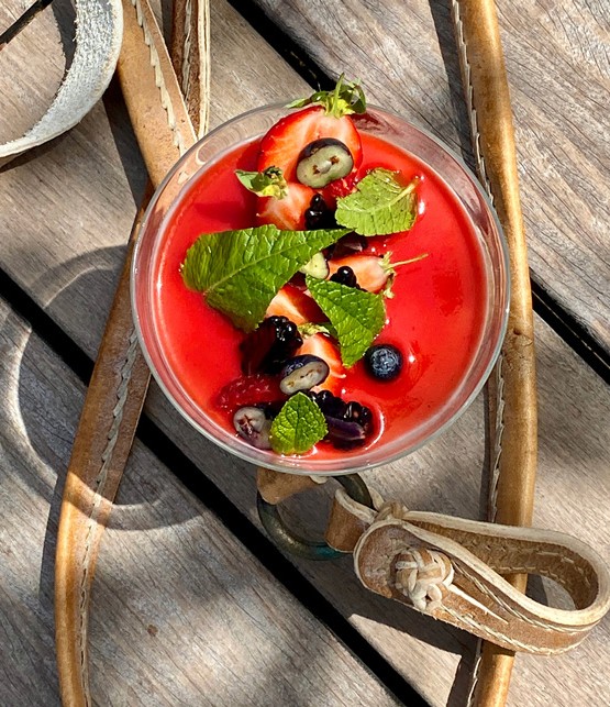 a glass of cocktail with a slime orange fruit