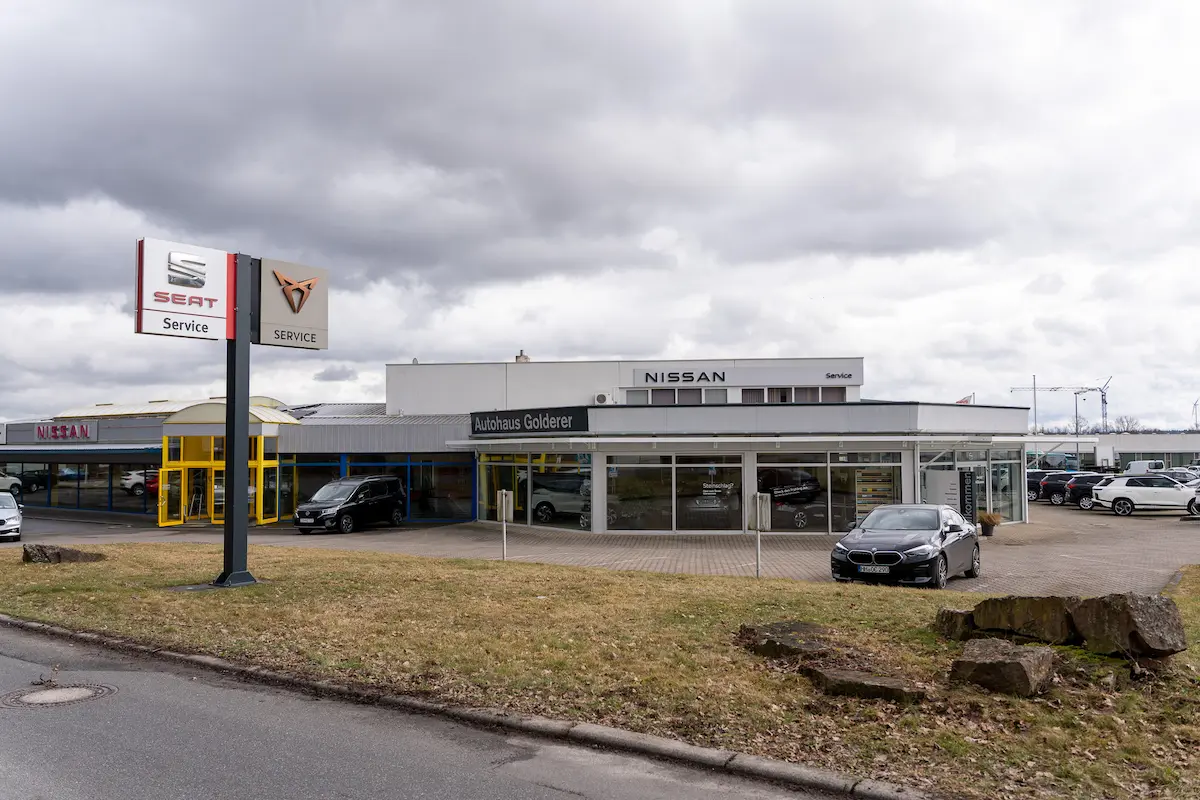 Außenansicht des Autohauses Golderer in Walldürn mit Verkaufsgebäude, Werkstatt und mehreren Fahrzeugen auf dem Gelände.