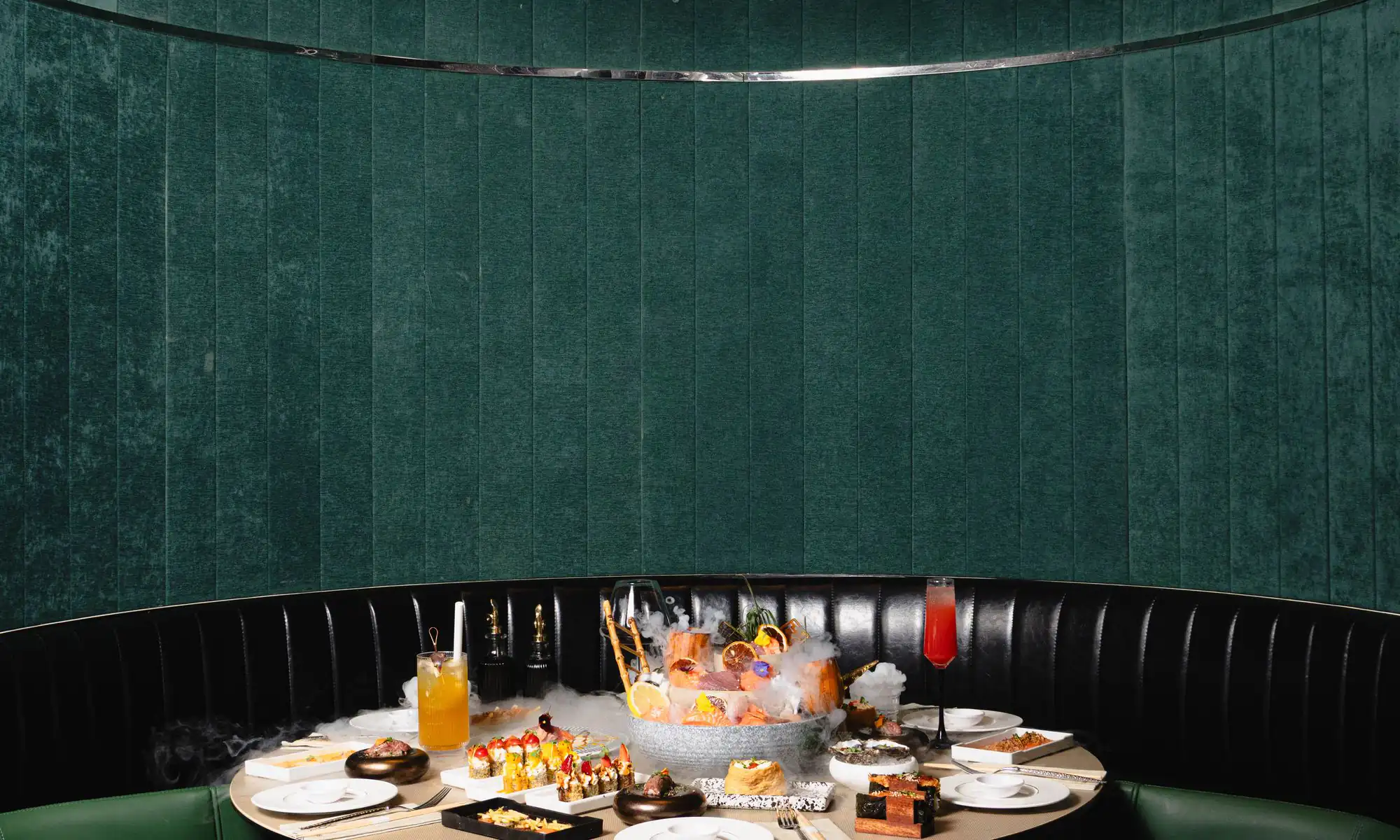 The fir-green velvet rotunda at Sushi Club Pontault-Combault, a round table set beneath the brass ring