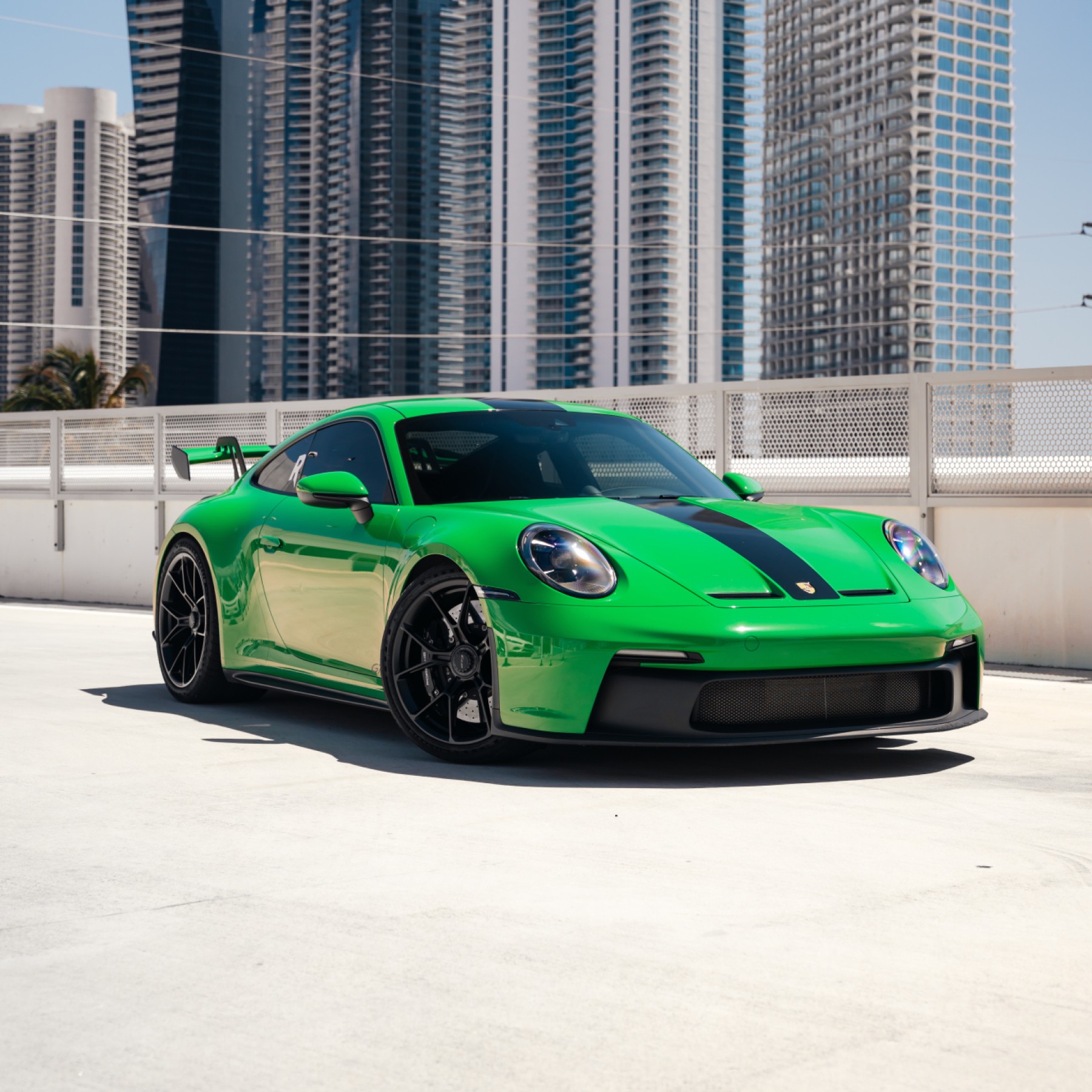 Front 3/4 view of a vibrant green Porsche 911 GT3 rental in Miami, showcasing its aggressive front fascia and track-ready design.