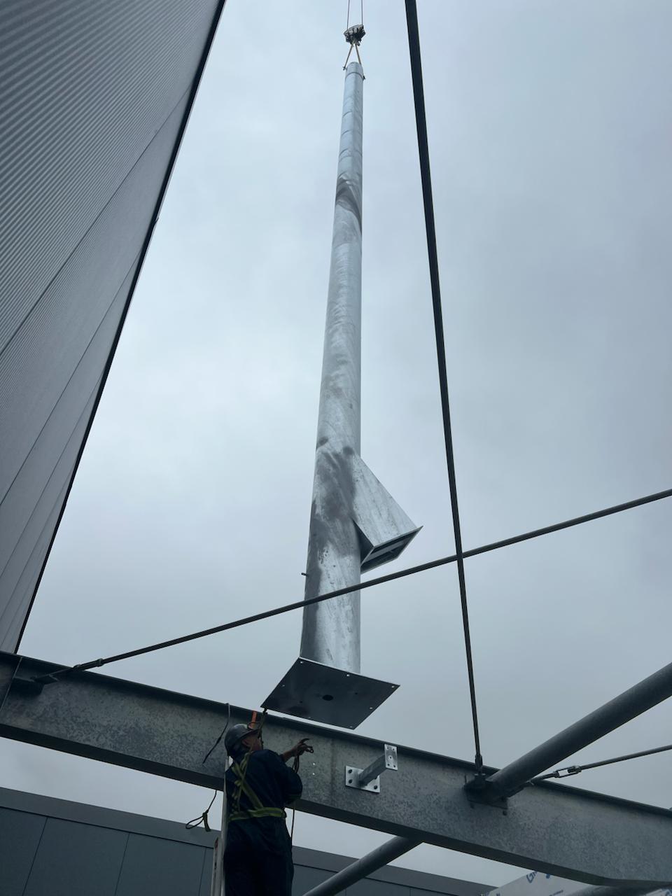 Crane lifting a tall galvanized steel vent stack