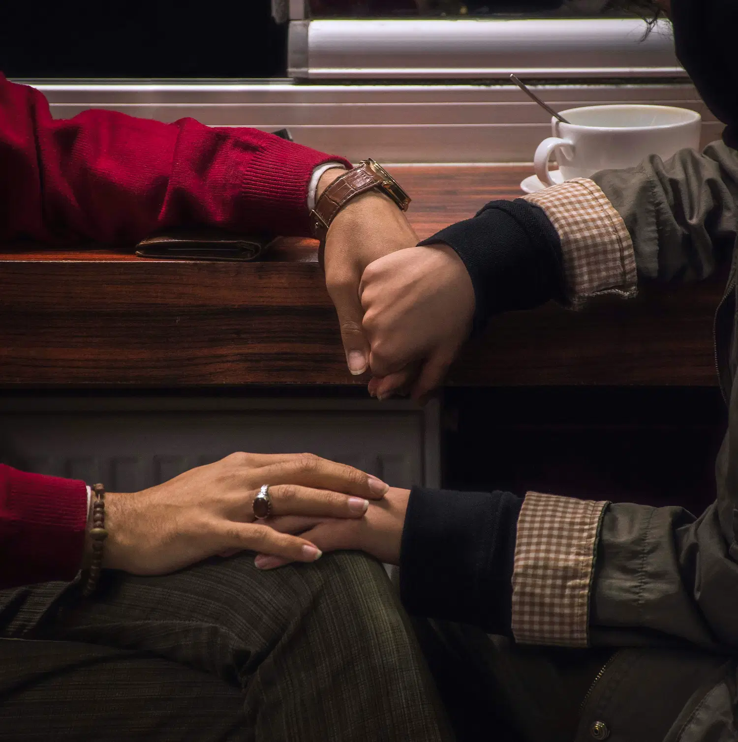 Two people holding hands across a table, symbolizing care, connection, and understanding in bisexual and pansexual affirming therapy in Los Angeles.