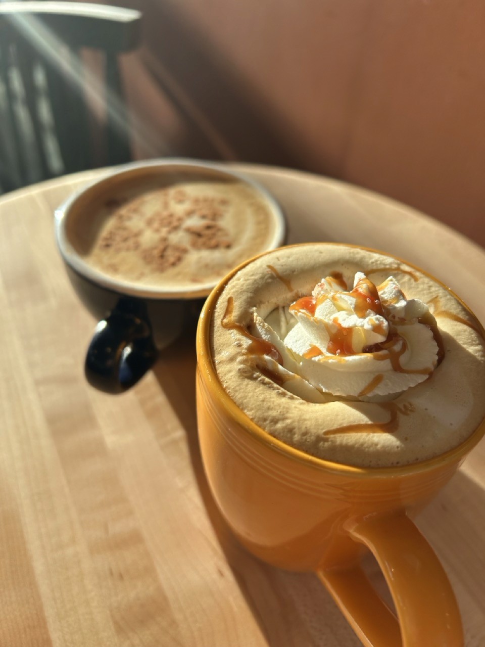 Warm coffee drinks in a blue and orange mug on a table in a Cadinho Cafe