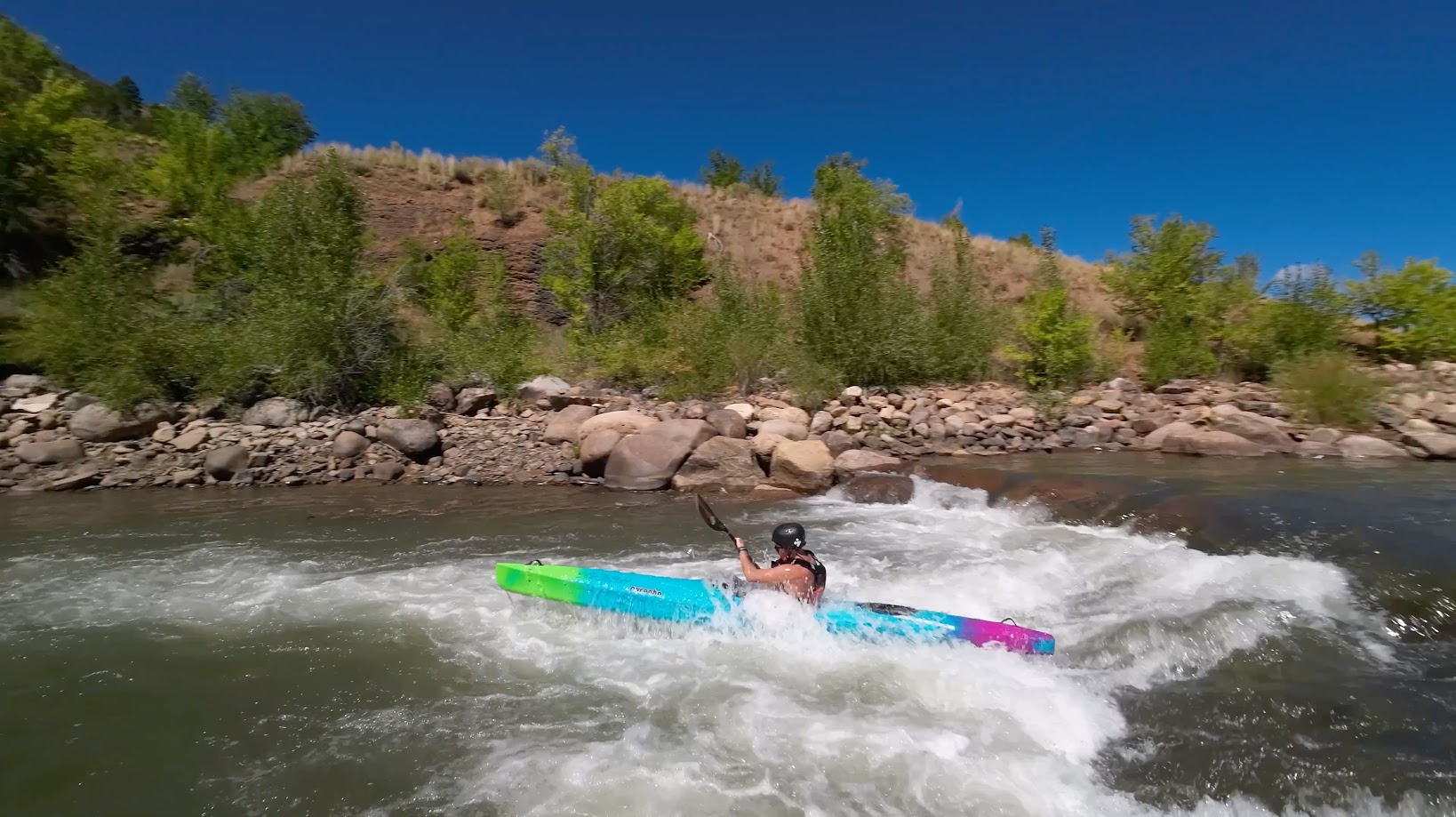 Kayaker driving through whitewater on the river, paddle raised