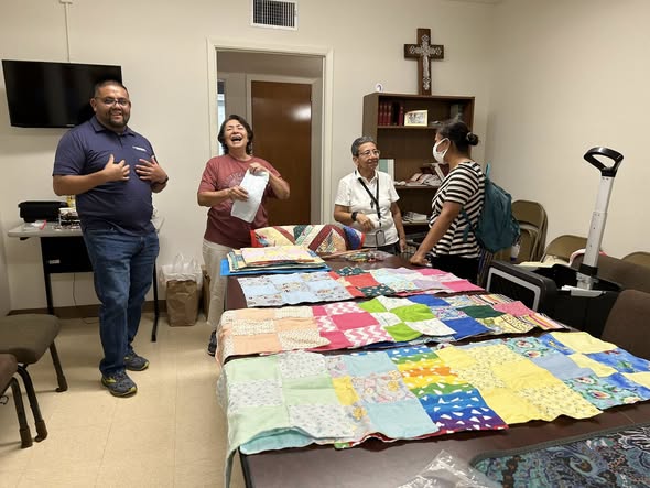 quilts on table with people behind them