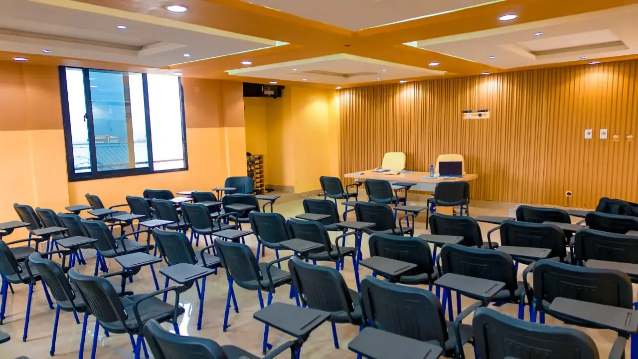 Salle de réunion avec rangées de chaises face à la table des intervenants.