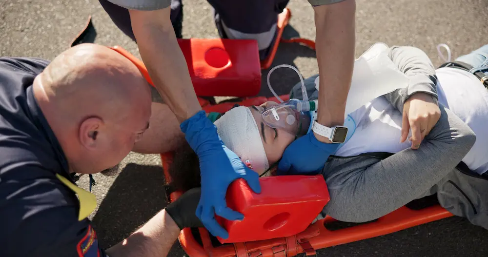 injured worker on with firefighters helping him